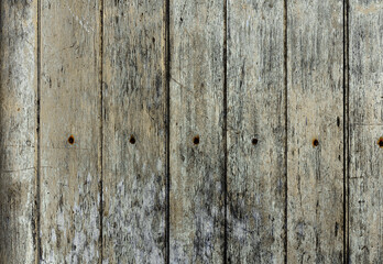 Texture of stained vertical planks facade. Old dirty rough siding of gnarled surface rural country wooden paneling. Messy aged laths.  Rustic grungy ranch lumber fence of hard boards for barn design