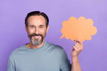 Portrait of cheerful handsome middle aged man hold speech bubble tell interesting news isolated on...