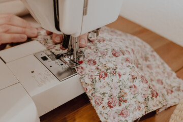 Close up of sewing machine. Crop view of hands of female tailor sewing on machine. Soft focus.