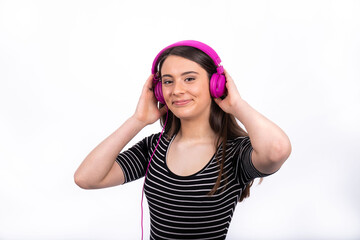 Portrait of beautiful smiling girl with long hair. The young woman wears jeans and a striped shirt and uses headphones to listen to music.
