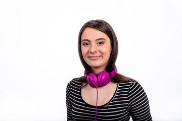 Portrait of beautiful smiling girl with long hair. The young woman wears jeans and a striped shirt and uses headphones to listen to music.