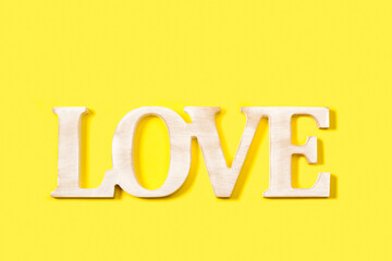 Palabra Love en letras de madera blanca rústica sobre un fondo amarillo brillante liso y aislado. Vista superior y de cerca. Copy space