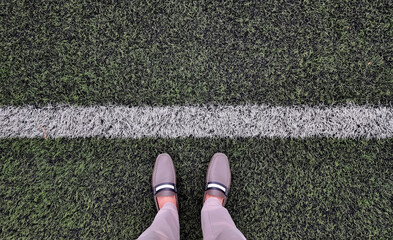 businessman in brown vintage casual shoes and beige slacks seen form above. relax standing of young businessman on green grass filed with starting line. close up of man legs for beginning concept.
