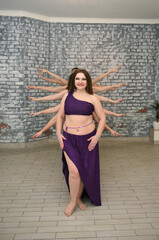 A group of beautiful girls in the outfits of oriental dancers in the studio dance a ritual dance imitating a multi-armed goddess. Fat girl dancer