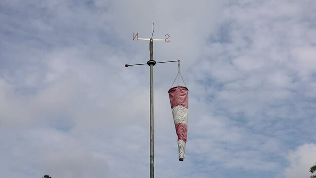 White and red windsock isolated on blue sky  
background. Check the wind blow direction concept