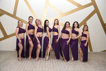 A group of beautiful girls in the outfits of oriental dancers in the studio stand in a row posing...