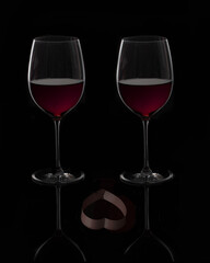 Dark and moody ,Two glasses of red wine with a heart reflection in the front