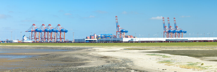 Panorama of container gantry cranes with industrial halls at the Jade Weser Port, deep water harbor...