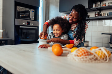 Family preparing healthy orange juice in the kitchen at home