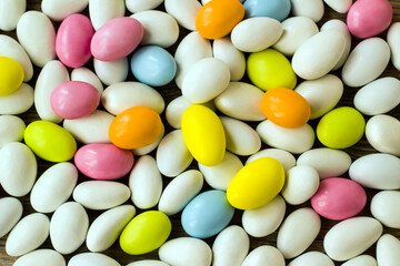 Pastel tones colored and chocolate covered almond candies background,fulled frame