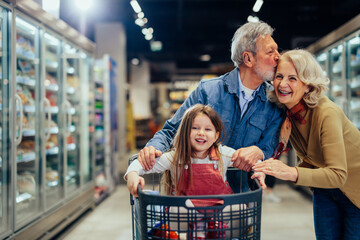 Happy grandparents and grandchild shopping at supermarket