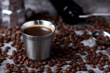 Metal coffee glass with espresso and coffee beans on a dark background