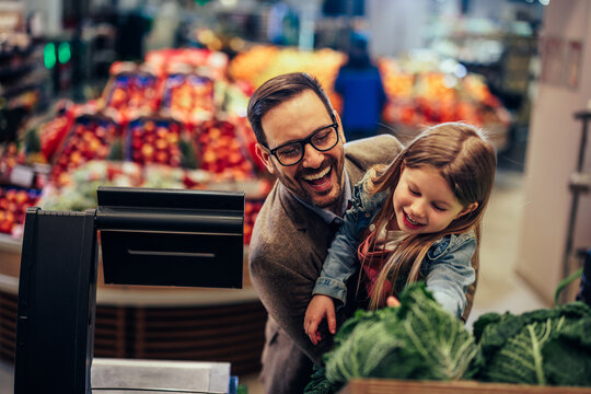 Father and daughter buying vegetables in market