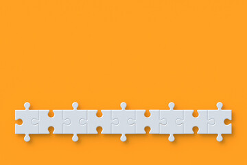 Row of unfinished jigsaw puzzle pieces on orange background. Copy space. Top view. 3d render