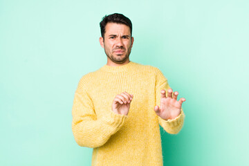 young handsome hicpanic man feeling disgusted and nauseous, backing away from something nasty,...