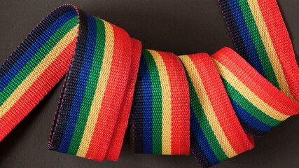 Rainbow spirally rolled textile tape on dark background