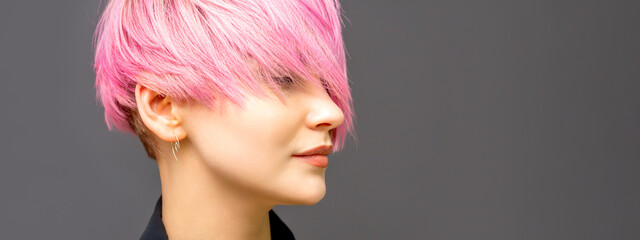 Profile of a beautiful young caucasian woman with short straight bob hairstyle dyed in pink color...