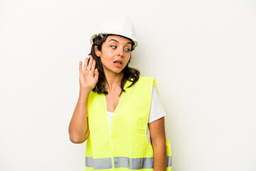 Young laborer hispanic woman isolated on white background trying to listening a gossip.