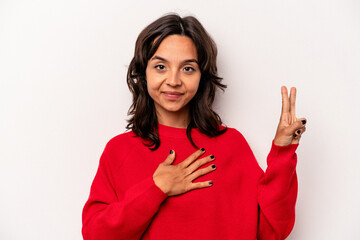 Young hispanic woman isolated on white background taking an oath, putting hand on chest.