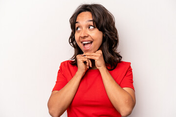 Young hispanic woman isolated on white background keeps hands under chin, is looking happily aside.