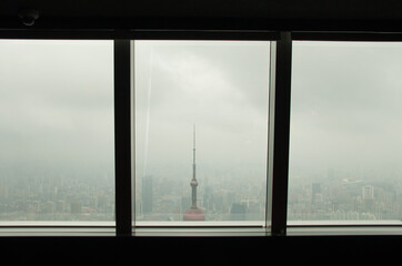 Shanghai Skyline is seen through a row of windows on a foggy, cloudy day making the city feel distant and surreal, like an unreachable painting-like place. 