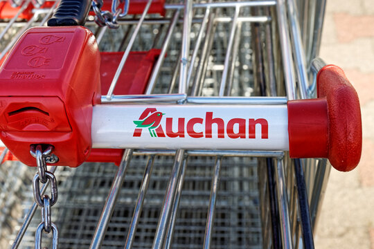 Close-up view of shopping trolley with Auchan hypermarket store logo.