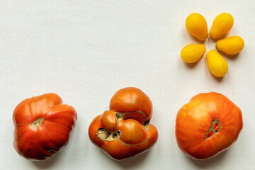 Top view of ripe organic tomatoes on white table with copy space.