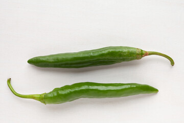 Green raw chili peppers top view on bright table. Home-grown pepper vegetables Numex Heritage Big Jim variety.
