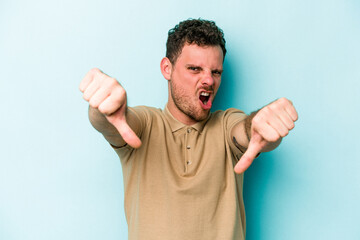 Young caucasian man isolated on blue background showing thumb down and expressing dislike.