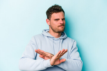 Young caucasian man isolated on blue background doing a denial gesture