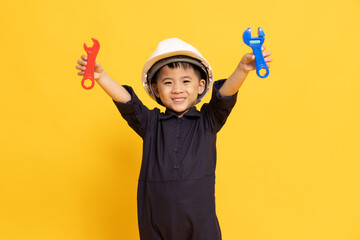 Asian little boy playing and showing repair tool isolated on yellow background, Technician kid concept