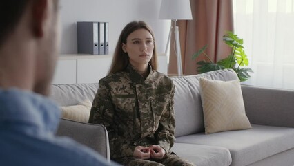 After war psychological recovery. Young depressed woman soldier in camouflage talking with man psychologist, free space