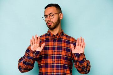 Young hispanic man isolated on blue background rejecting someone showing a gesture of disgust.