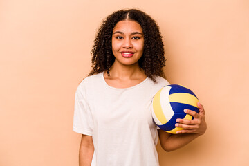 Young African American woman playing volleyball isolated on beige background happy, smiling and cheerful.