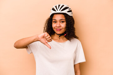 Young hispanic woman wearing a helmet bike isolated on blue background showing a dislike gesture, thumbs down. Disagreement concept.