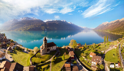 Stunning idylic nature scenery of lake Brienz with turquoise waters. Switzerland, Bern canton. Aerial view with little church in the morning light - obrazy, fototapety, plakaty