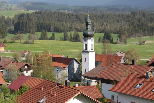Blick auf ein Dorf im Allgäu mit Kirchturm, im Hintergrund das hügelige Voralpenland