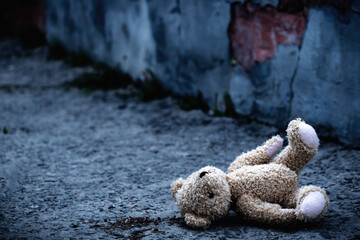 Lost childhood, loneliness, pain and depression. Conceptual image: dirty Teddy bear toy lying down...