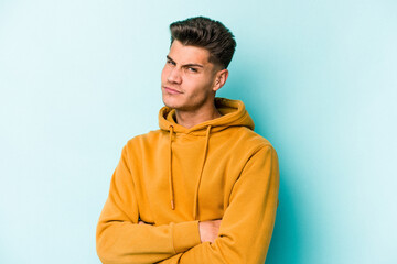 Young caucasian man isolated on blue background unhappy looking in camera with sarcastic expression.