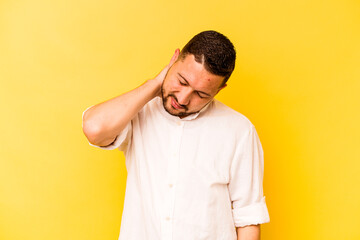 Young hispanic man isolated on yellow background having a neck pain due to stress, massaging and touching it with hand.