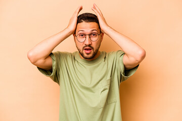 Young hispanic man isolated on beige background being shocked, she has remembered important meeting.