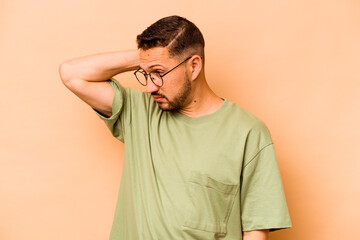 Young hispanic man isolated on beige background tired and very sleepy keeping hand on head.