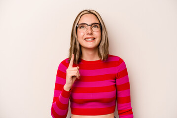 Young caucasian woman isolated on white background indicates with both fore fingers up showing a...
