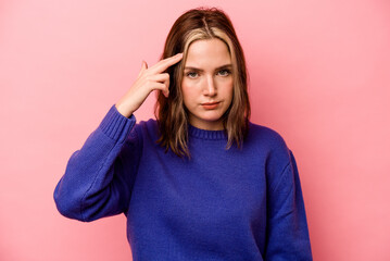 Young caucasian woman isolated on pink background pointing temple with finger, thinking, focused on a task.