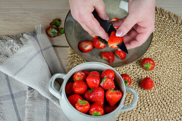 Zdjęcie przedstawia dłonie które odbierają truskawki. Obcinanie zielonej części z truskawki.