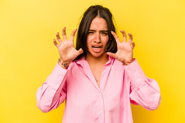 Young hispanic woman isolated on yellow background upset screaming with tense hands.