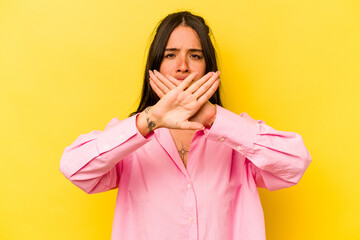 Young hispanic woman isolated on yellow background doing a denial gesture