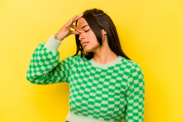 Young hispanic woman isolated on yellow background having a head ache, touching front of the face.