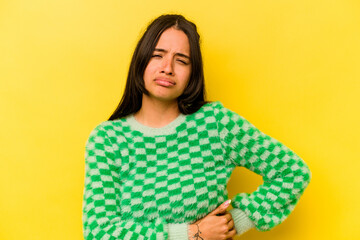 Young hispanic woman isolated on yellow background having a liver pain, stomach ache.