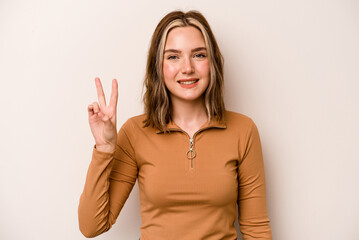 Young caucasian woman isolated on white background joyful and carefree showing a peace symbol with fingers.